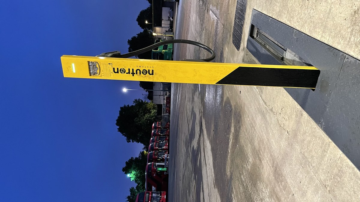 Neutron NSNF0015GRC in-ground charger unit at night in a London bus depot, flush with tarmac surface