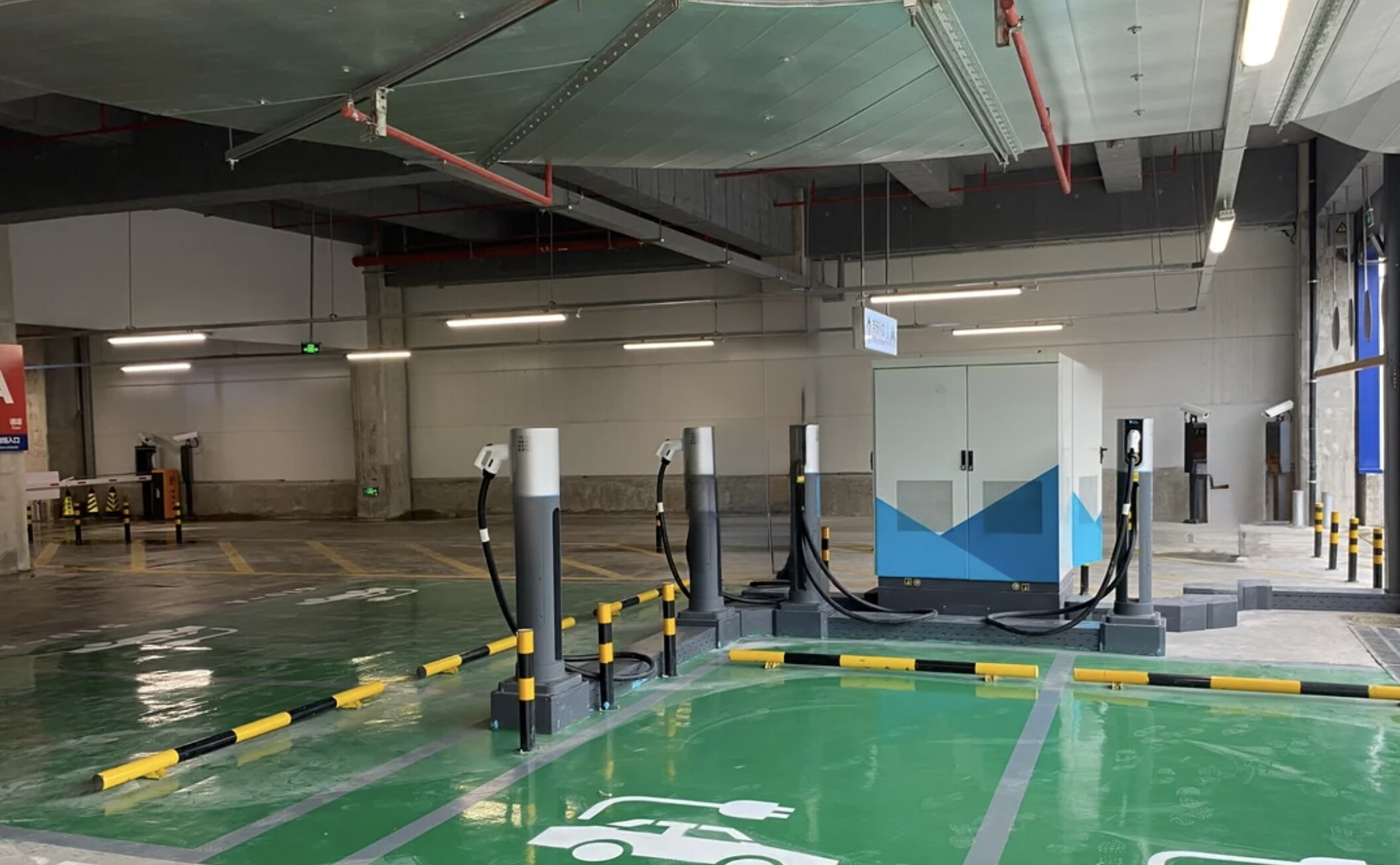 Rapid deployment EV charging installation in an underground car park with green EV bays, showing group charger dispensers on surface-mounted bases alongside a freestanding power cabinet