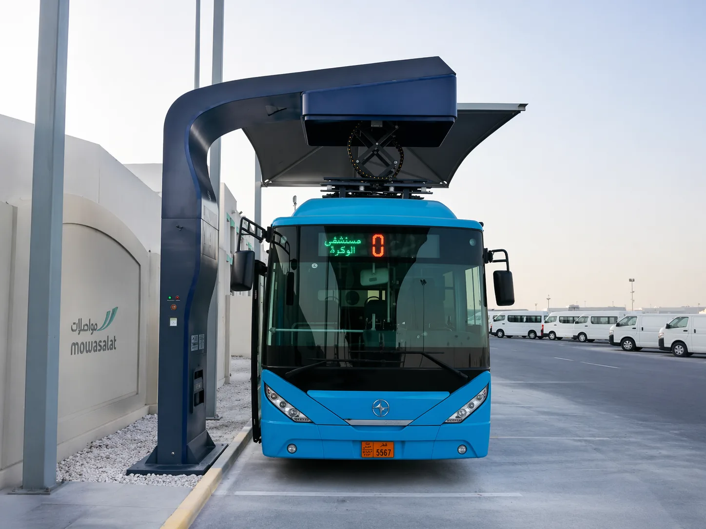 Electric bus under pantograph charger at bus depot